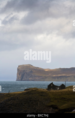 Haus außerhalb des Dorfes Hofsos, Nordwesten Islands. Thordarhofdi Kap im Hintergrund. Stockfoto