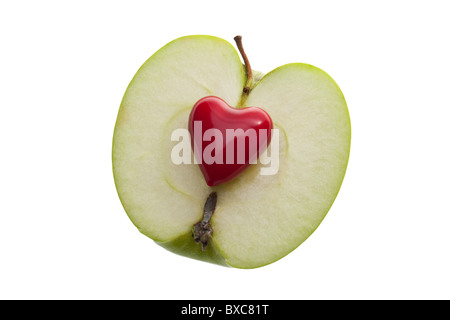 ein kleines rotes Herz auf einem geschnittenen grünen Apfel auf einem weißen nahtlosen Hintergrund Stockfoto