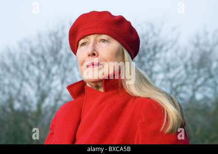 Eine schöne ältere Frau in ihren Sechzigern trug einen roten Mantel und Barett. Stockfoto