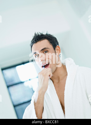 Mann im weißen Bademantel Zähneputzen Stockfoto