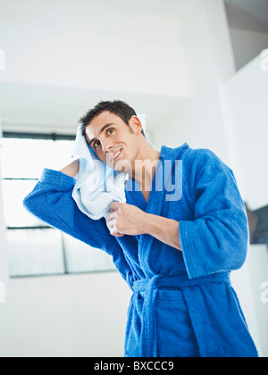 Mann im Bademantel trocknet Haare Stockfoto