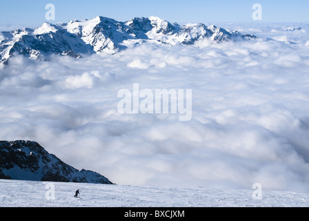 Eine Skifahrerin auf dem Gletscher von La Meije in La Grave, Frankreich, Skifahren über einige dicke Wolken. Stockfoto