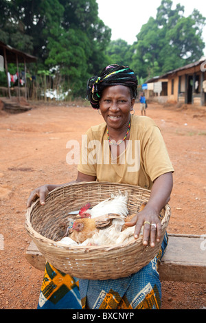Eine Frau sitzt auf dem Markt mit einem Korb voller Hühner in Port Loko, Sierra Leone, Westafrika. Stockfoto