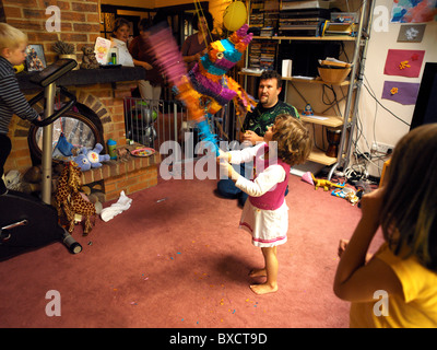 Vier Jahre alten schlagen ein Pinata auf Geburtstagsparty in England Stockfoto