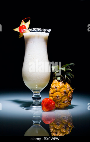 Pina Colada cocktail mit Kirsche umgeben von Ananas und Erdbeere Stockfoto