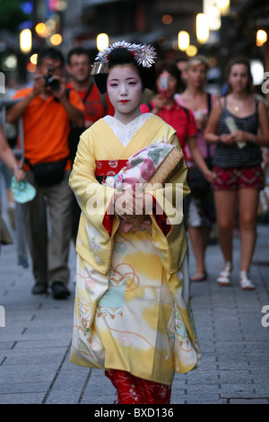 Maiko Geisha, gefolgt von einer Gruppe von Touristen und Fotografen auf einer Straße im Stadtteil Gion in Kyoto Japan Stockfoto