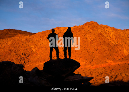 Zwei Silhouette männliche Rucksacktouristen posieren für ein Porträt beim stehen auf einem Steinhaufen beim Wandern durch Death Valley Confidenc Stockfoto