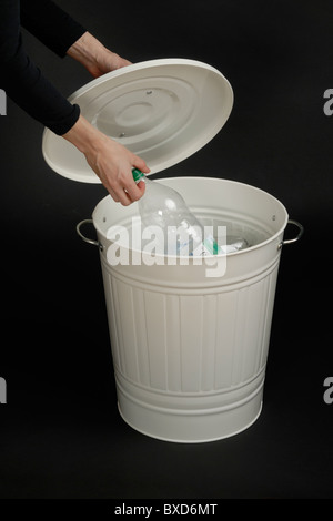 Person setzen eine Plastikflasche in Papierkorb, auf schwarzem Hintergrund isoliert Stockfoto