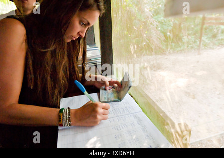 Eine junge Frau unterzeichnet ein Logbuch mit ihrem Passport-Konto im Amazonas-Regenwald. Stockfoto