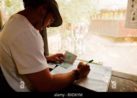 Ein junger Mann unterschreibt ein Logbuch mit seinen Pass in den Amazonas-Regenwald. Stockfoto