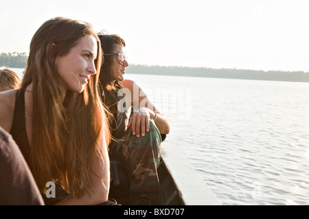 Zwei junge Frauen schauen in den Sonnenuntergang über Sandoval See im Amazonas-Regenwald. Stockfoto