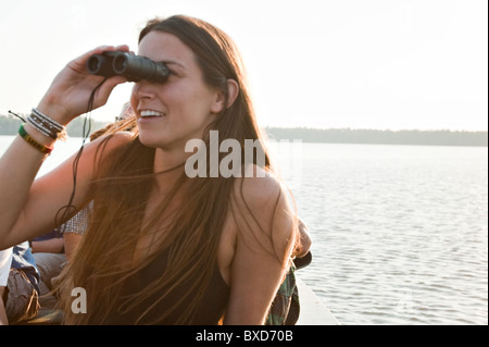 Eine junge Frau schaut durch ein Fernglas auf verschiedenen Arten der Vögel auf Sandoval See im Amazonas-Regenwald. Stockfoto