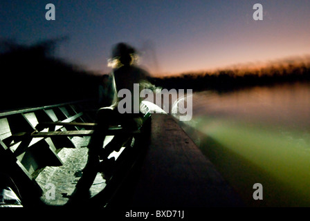Dorian SImon Paddel eine große hölzerne Kanu bei Sonnenuntergang in Sandoval See. Stockfoto