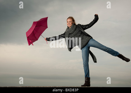 Frau kämpft mit einem Regenschirm im Herbst, windig Stockfoto