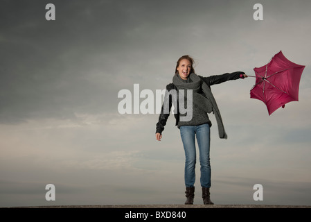 Frau kämpft mit einem Regenschirm im Herbst Stockfoto