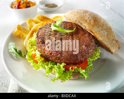 Beef-Burger in einem Vollkorn Brötchen mit Salat und Pommes frites Stockfoto