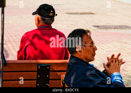 Asiatische Männer sitzen auf der Parkbank in Hongkong China Stockfoto