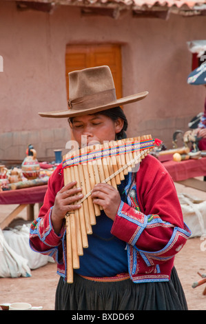 Eine peruanische Frau in traditioneller Kleidung spielt das Pan-Rohr auf dem Platz in Racchi, Peru, Südamerika. Stockfoto