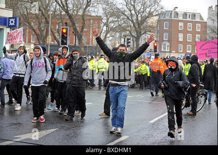 Masse Demonstration in Brighton gegen Regierung Kürzungen der Hochschulfinanzierung - maskierte Demonstranten gehen vor der Polizeiabsperrung Stockfoto