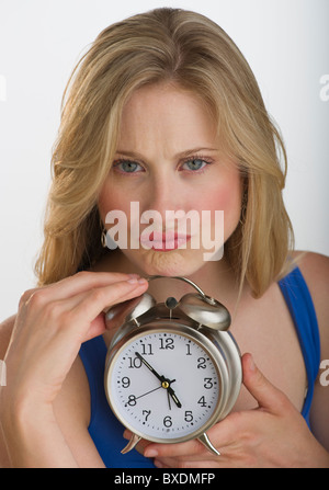 Aufgeregt blonden Frau mit Wecker Stockfoto