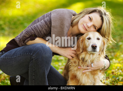 Schöne junge Frau posiert vor der Kamera mit ihrem Golden Retriever Hund Stockfoto