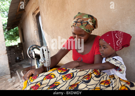 Ein junges Mädchen hilft ihre große Schwester eine Kleid in Dodoma, Tansania, Ostafrika zu nähen. Stockfoto