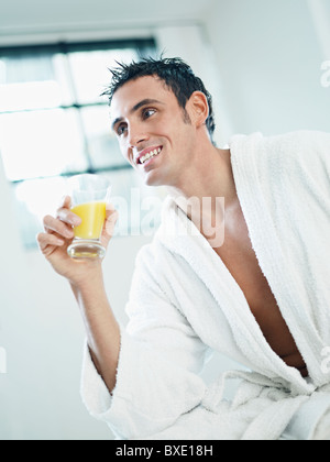 Mann trinkt Orangensaft im Bademantel Stockfoto