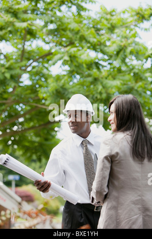 Frau im Gespräch mit Architekt Holding Blaupausen Stockfoto