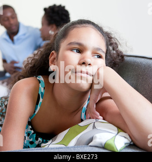 Gelangweilt Mädchen sitzen auf der Couch mit Eltern Stockfoto