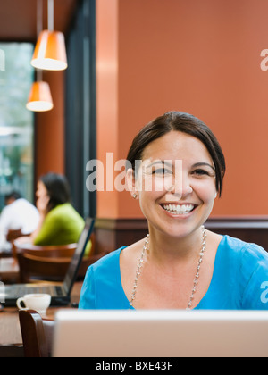 Lächelnde Frau sitzt am Tisch im restaurant Stockfoto