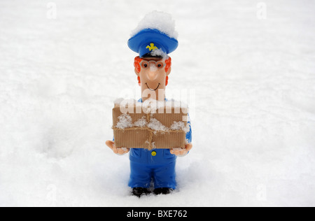 POSTBOTE FIGUR MIT PARZELLE IN VERSCHNEITEN EISIGEN WETTERBEDINGUNGEN RE POSTAMT LIEFERUNGEN VERZÖGERUNGEN ETC. UK POST WINTERDIENST Stockfoto