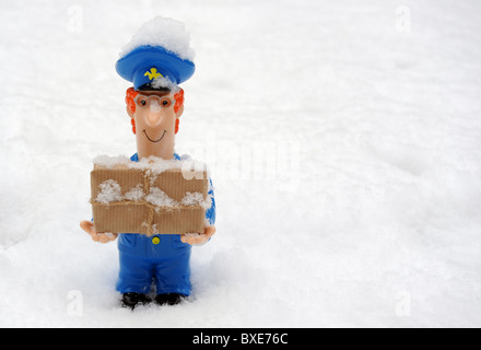 POSTBOTE FIGUR MIT PARZELLE IN VERSCHNEITEN EISIGEN WETTERBEDINGUNGEN RE POSTAMT LIEFERUNGEN VERZÖGERUNGEN ETC. UK POST WINTERDIENST Stockfoto