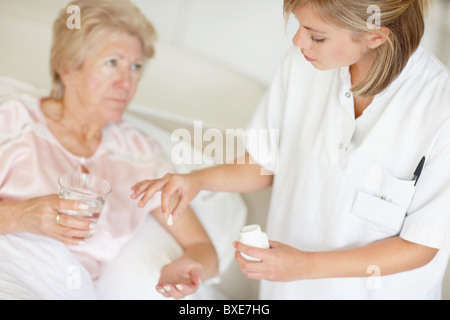 Krankenschwester, die Pille zu senior Frau geben Stockfoto