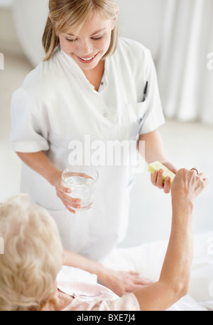 Krankenschwester, die Pille zu senior Frau geben Stockfoto
