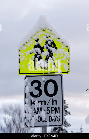 Schneebedeckte Schule Zone Tempolimit Schild in Winter-Victoria, British Columbia, Kanada. Stockfoto