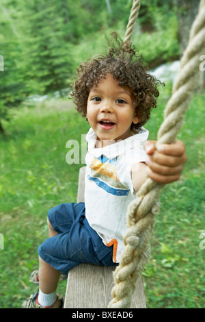 Süße junge Kind sitzt auf Schaukel Stockfoto