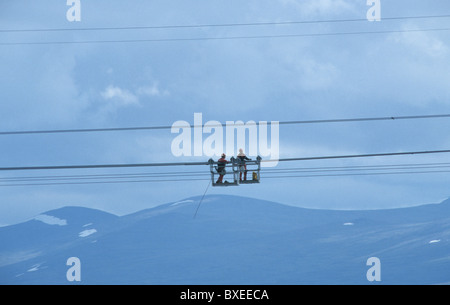 Bauarbeiter arbeiten an Energiekabeln hoch in die Luft, Hubschrauber Stockfoto