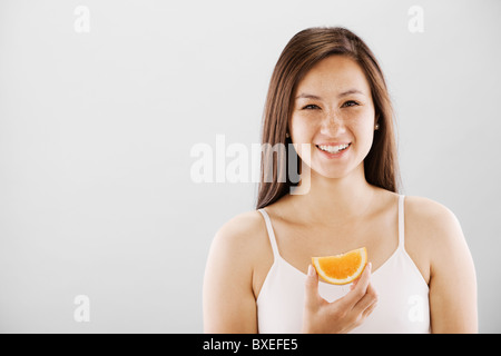 Frau hält eine Orangenscheibe Stockfoto