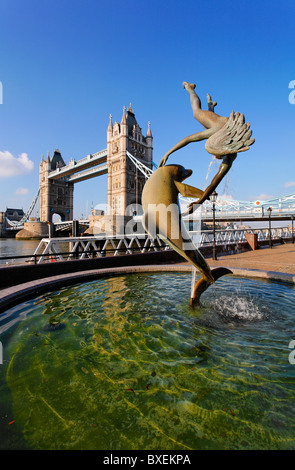 Die Tower Bridge und Mädchen spielen mit Dolphin Statue, London, UK Stockfoto