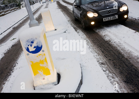 Beleuchtete Straße Poller und vorbei an Mercedes Auto bei winterlichen Schnee in Südlondon. Stockfoto