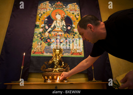 Der buddhistische Mönch Nagasiddhi zündet Kerzen im Altarraum an Rivendell buddhistischen Retreat Center, East Sussex, England. Stockfoto