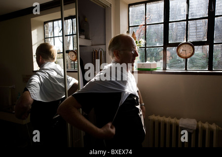 Priester setzt auf seine Amice vor Frühmesse in Sakristei (Sakristei) am St.-Laurentius Kirche in Feltham, London. Stockfoto