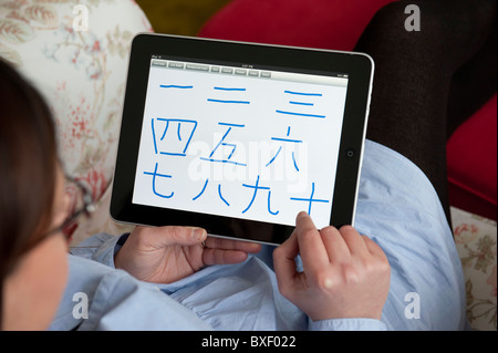 Frau schreiben chinesische Schriftzeichen für die Zahl von 1 bis 10 auf einem iPad Tablet-computer Stockfoto