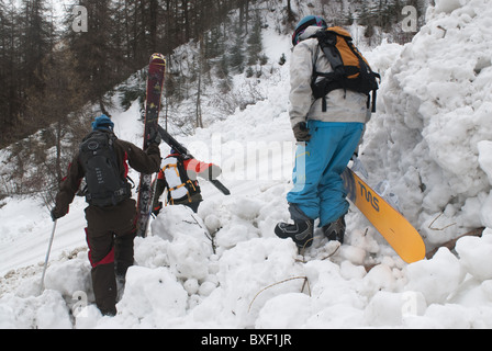 Zwei Skifahrer und Snowboarder zu Fuß über frische lawinengefährdetem Gelände. Stockfoto