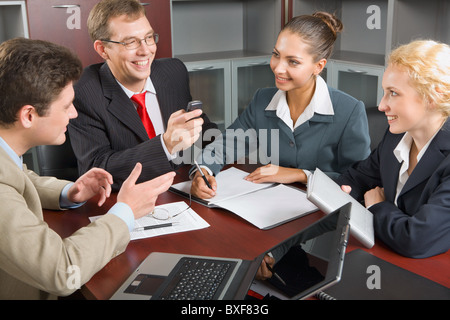 Porträt von vier erfolgreiche Menschen rund um den Tisch versammelt und diskutieren eine neue Geschäftsstrategie im Sitzungssaal Stockfoto
