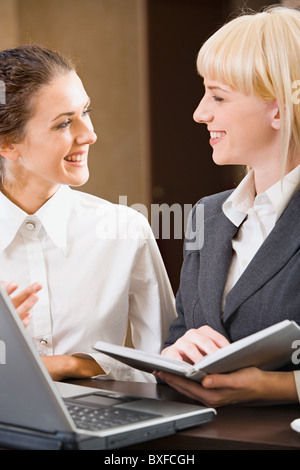 Zwei zeitgenössische lächelnde Geschäftsfrauen sind im Chat Stockfoto