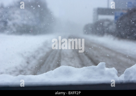 Auto mit Schnee auf der Motorhaube fahren entlang einer kalten gefrorenen Straße an einem kalten verschneiten Wintertag Belfast Nordirland Stockfoto