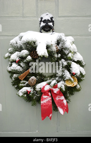 Traditionellen Adventskranz mit Schnee auf einer Haustür. Stockfoto