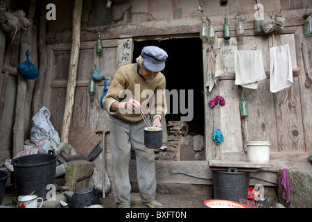 Ein Alter Mann vor seinem rustikalen und schmutzigen hölzernen Haus in einer abgelegenen Bergdorf in der Provinz Gansu in China. Stockfoto