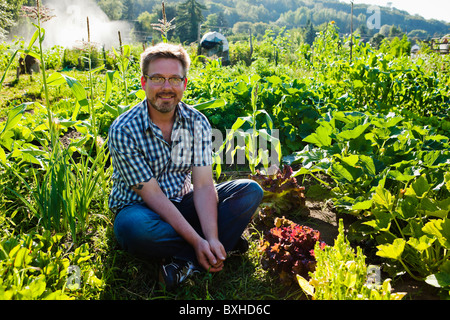 Porträt eines jungen Mannes, die Arbeit in seinem Garten des Grundstückes in einem Gemeinschaftsgarten in Seattle, WA, USA Stockfoto